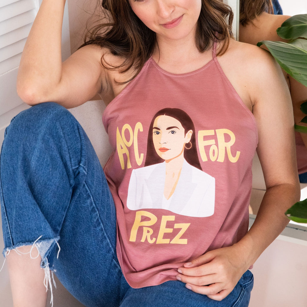 Model is wearing Pink AOC for Prez tank top. High neck, flow/drapey fit. 65% polyester/35% viscose fabric that is pre-shrunk. Model is wearing size small. Sizes are S-3XL