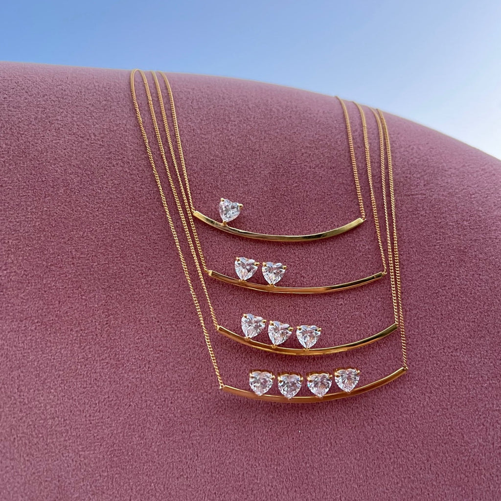 I carry your heart necklace. 4 versions available with 1, 2,3 & 4 heart stones. Stones resting on top of gold bar. Sterling silver/ gold plated. 