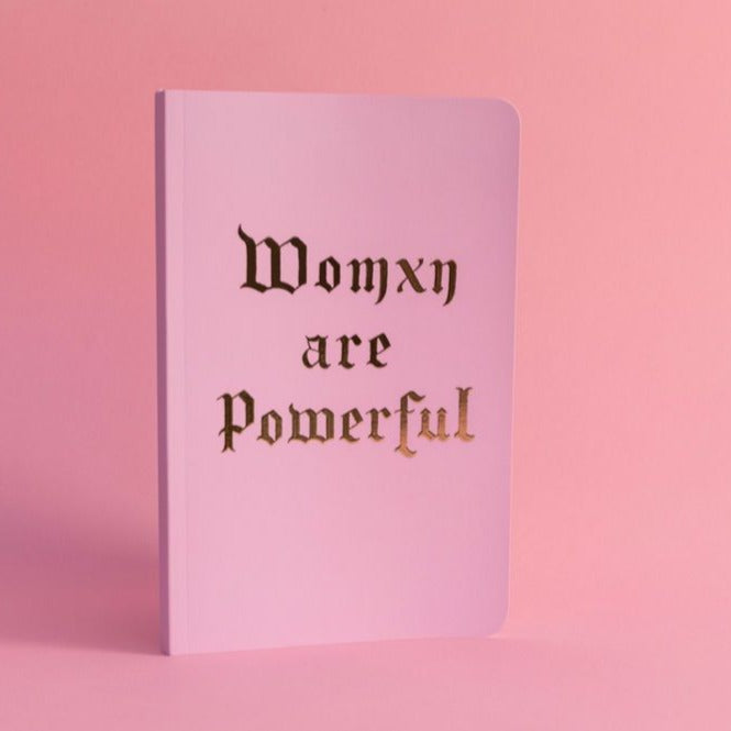 Womxn Are Powerful Lux Notebook is matted pink with gold foil lettering. Made from premium recycled paper. 8.25 inches x 5.25. 144 thick pages 
